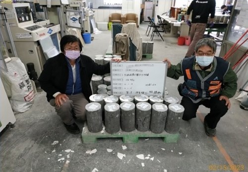 二人同時進行拿取混凝土抗壓試驗圓柱試體標示板